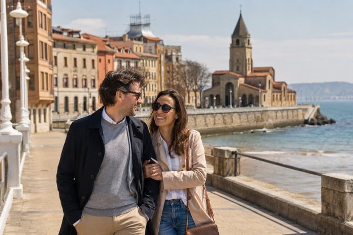 Pareja adulta en Gijón con Cimavilla y el litoral al fondo